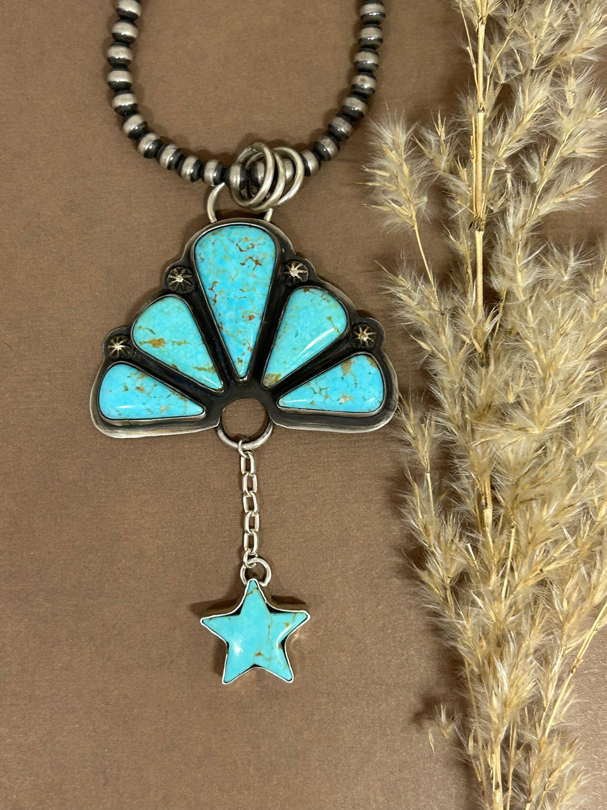 Sonora turquoise set in sterling silver in a naja design with a turquoise star accent.