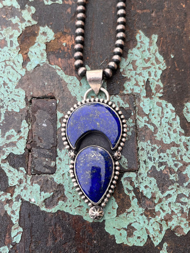 Lapis stones, crescent moon and teardrop shaped, set in sterling silver. The stones are accented with silver bead wire and silver stars.  The pendant is 3 inches long and 1.25 inches wide.