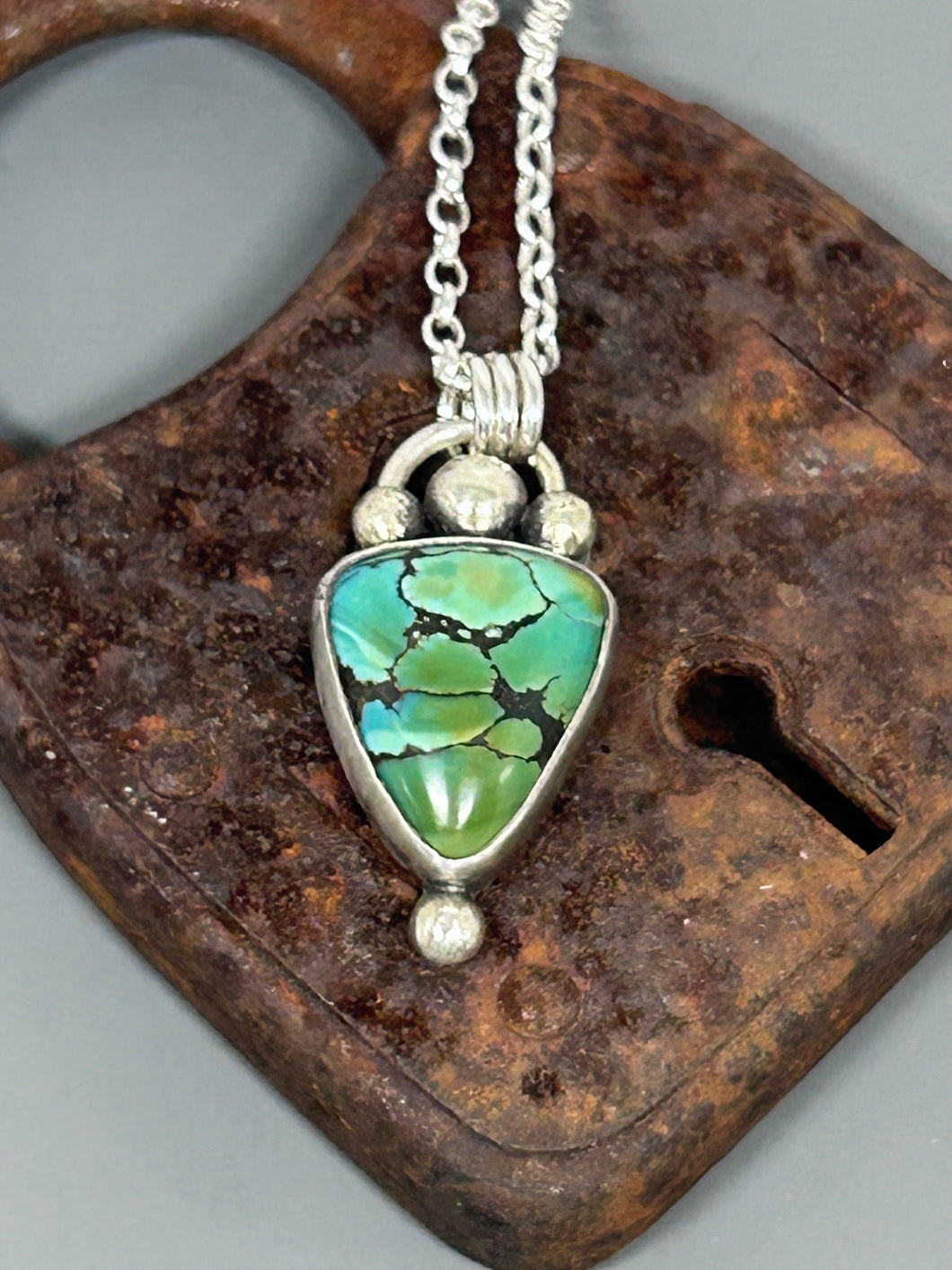 Triangle shaped polychrome Hubei turquoise set in sterling silver on an 18 inch sterling silver chain.