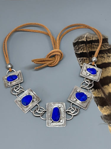 Blue Lapis set in sterling silver on two black plates accented with silver flattened balls.  The silver portion of the necklace is 8 inches the leather portions are 22 inches total making the necklace 30 inches long but adjustable to tie at your desired length.