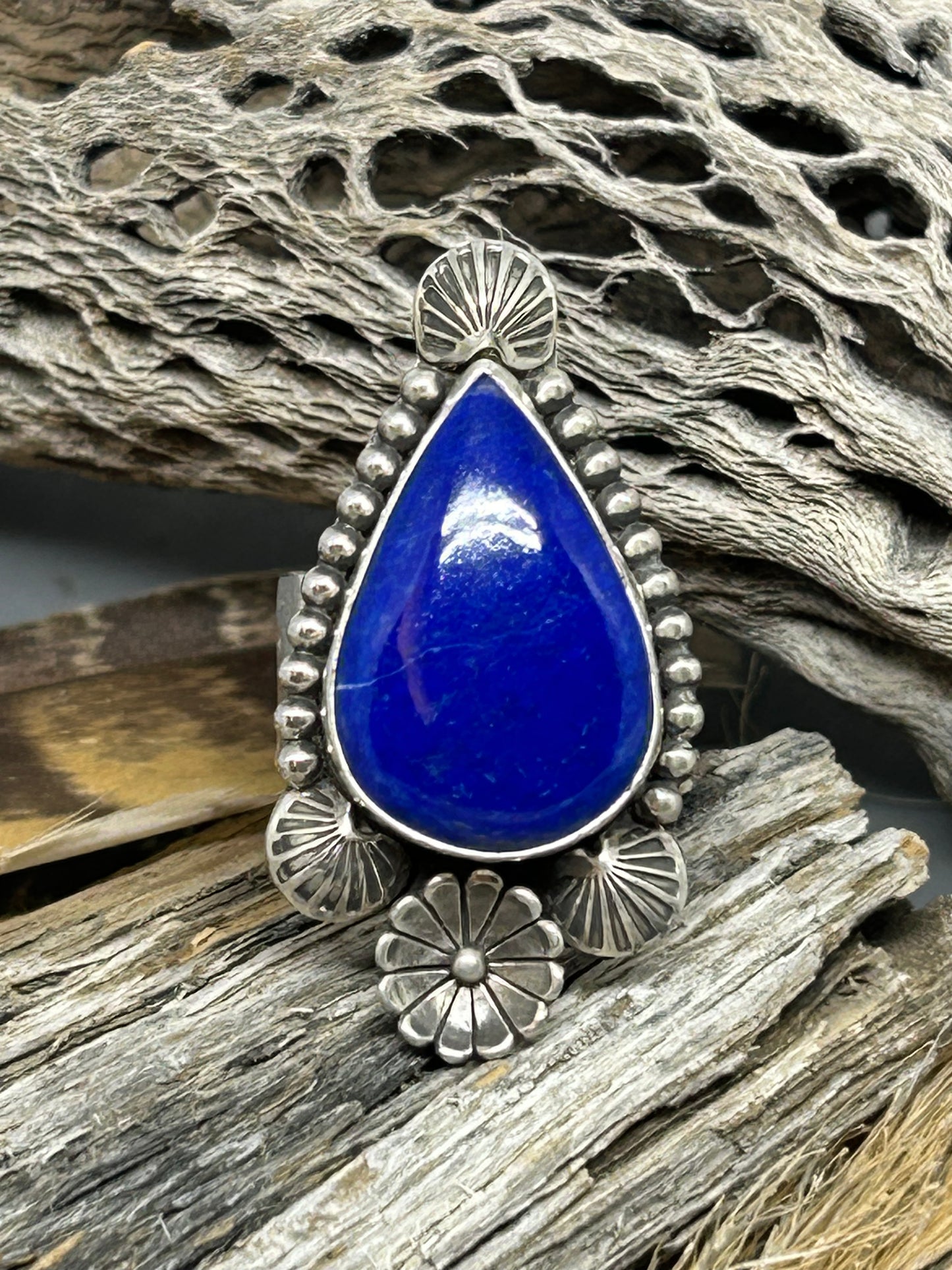 Lapis set in sterling silver accented with sterling silver flower hand stamped designs and bead wire. The band is wide hammered silver size 8.