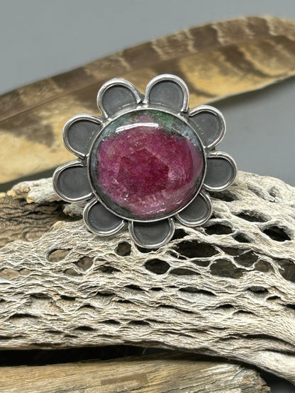 Round Ruby stone set in a sterling silver flower setting. The band is wide hammered sterling silver with the word bloom hand stamped on it, size 9.