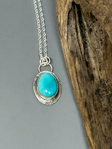 Blue oval Royston turquoise set in a distressed silver setting and hangs on an 18 inch sterling silver chain.