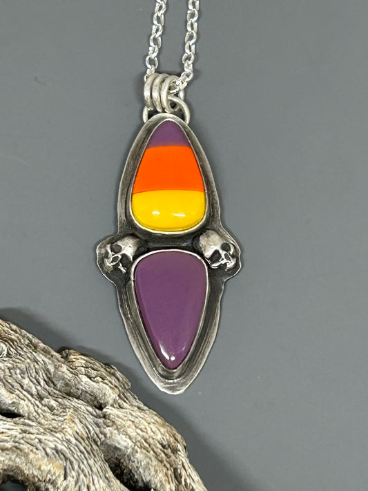 Halloween themed cabochons colored purple, orange and yellow. These cabochons are set in sterling silver and accented with sterling silver hand cast skulls. This pendant hangs on an 18 inch sterling silver chain.