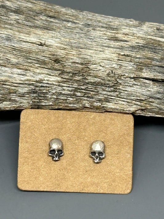 Small sterling silver skull stud earrings with sterling ear posts and backs.