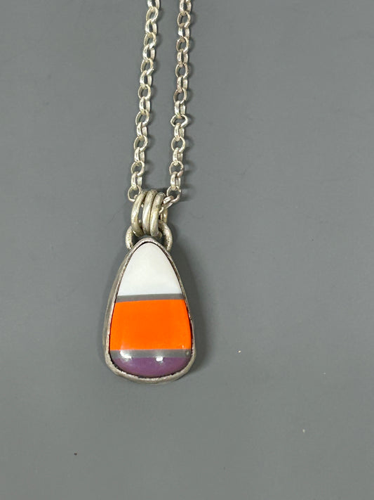 Candy corn cabochon colored white orange and purple. Set in sterling silver with a soft patina. This pendant hangs on an 18 inch sterling silver chain.