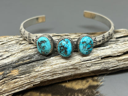 Three pieces of oval Morenci turquoise set in fin silver serrated bezels stop a six inch sterling silver 4 gauge hand stamped cuff.