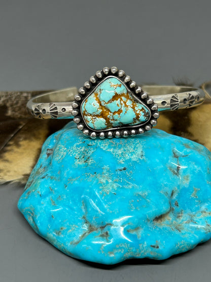 Godber turquoise nugget set in sterling silver on a 6 inch 4 gauge hand stamped band with a soft patina. This bracelet is adjustable.