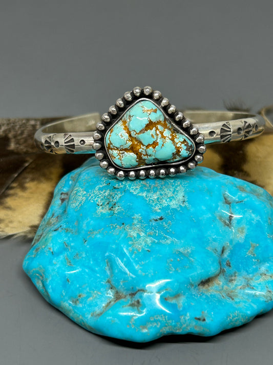 Godber turquoise nugget set in sterling silver on a 6 inch 4 gauge hand stamped band with a soft patina. This bracelet is adjustable.