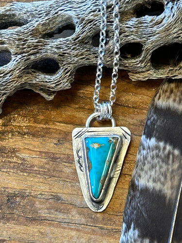 Triangle shaped Royston turquoise set in a rustic distressed setting on an 18 inch sterling silver chain.