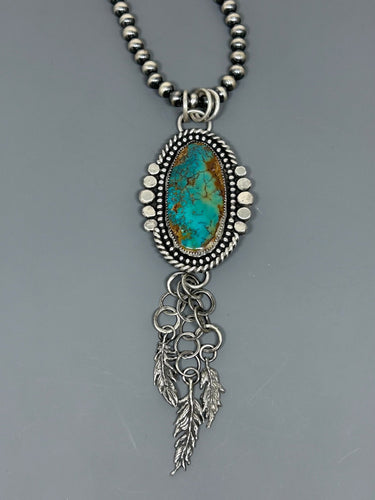 Southwestern pendant. High grade Royston Turquoise set in sterlin gsilver accented with silver bead wire, twist wire, hammered balls and three dangling sterling silver hand cast feathers.