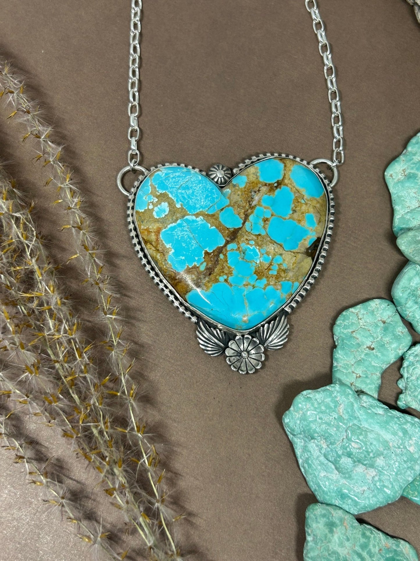 This statement heart necklace holds mine number 8 turquoise set in sterling silver accented with silver bead wire leaves and a flower. Hangs on 18 inches of sterling silver chain.