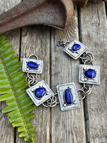 Five lapis stones set in sterling silver set on two plates of sterling silver with a soft patina.  This sterling silver link bracelet is just over 8 inches with a toggle clasp.  Handmade by Taylor Made Silver.